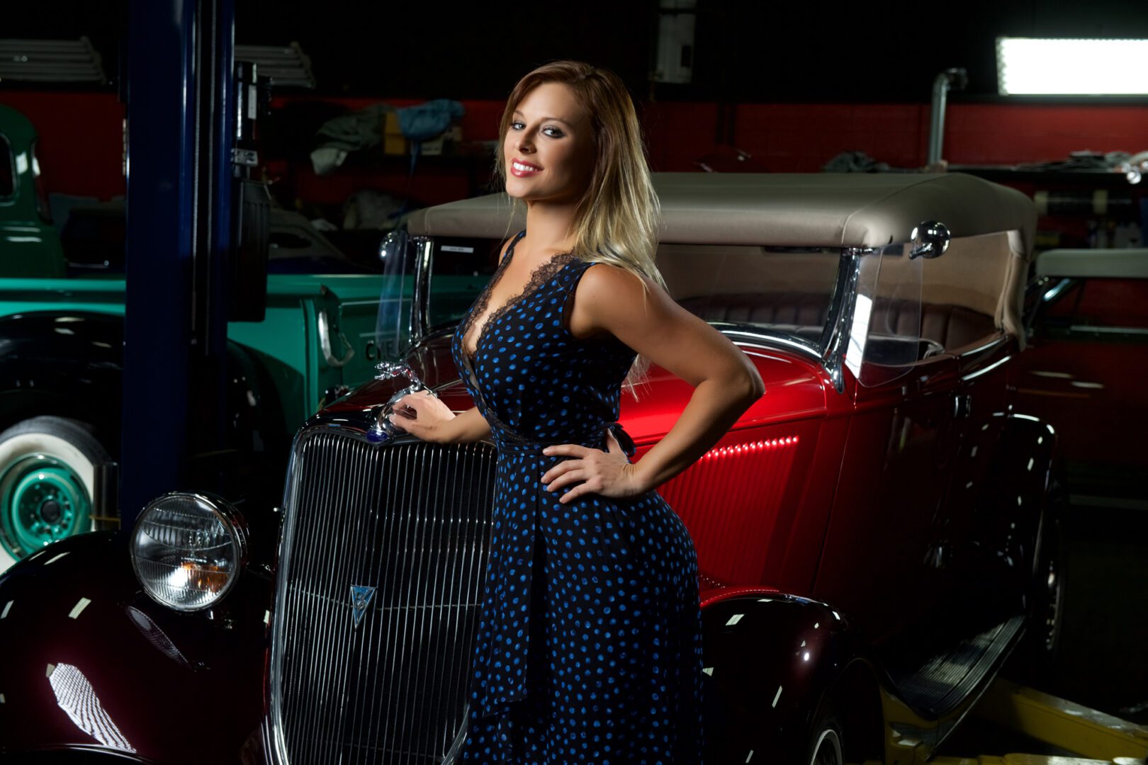 Model posing beside red vintage convertible