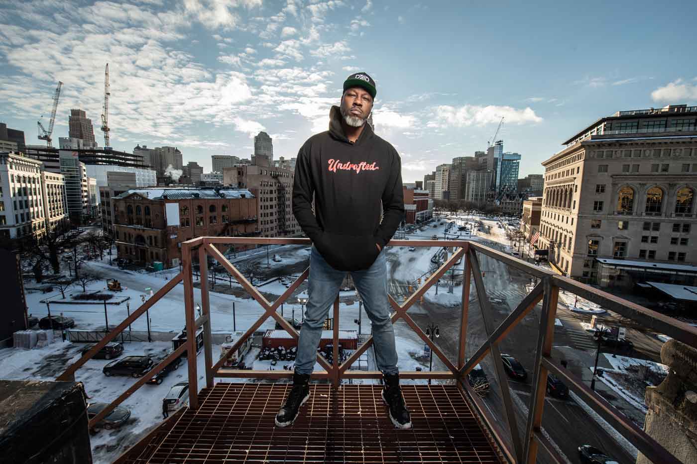 Hoodie-clad figure framed by winter urban skyline
