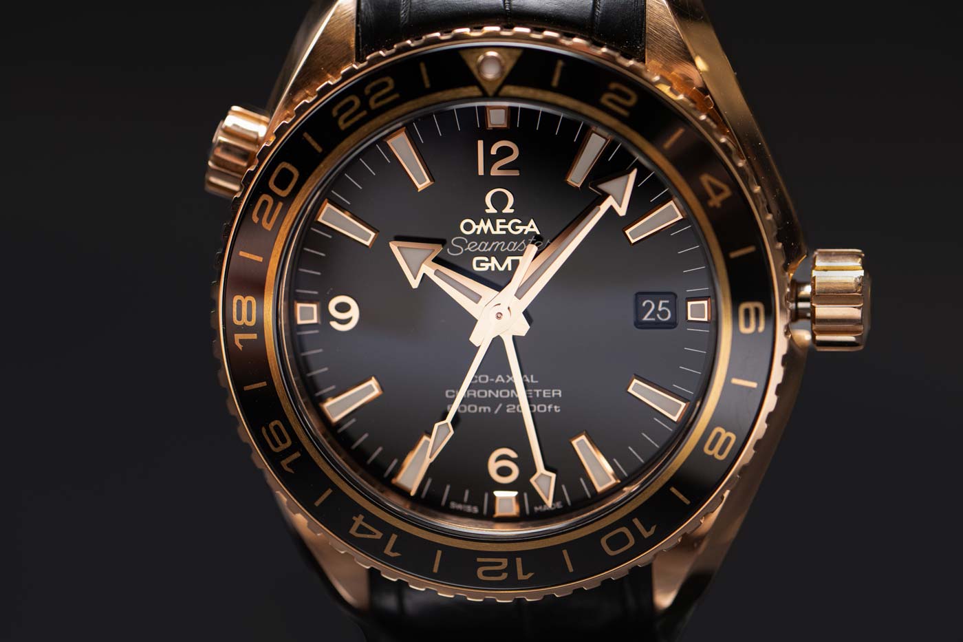 Close-up of a luxury Omega GMT wristwatch with a black dial and rose gold case.